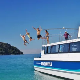 Group of people leaping off the Abel Tasman Sea Shuttle into turquoise water