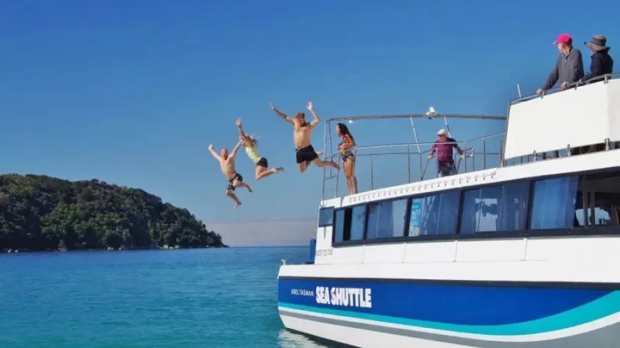 Group of people leaping off the Abel Tasman Sea Shuttle into turquoise water