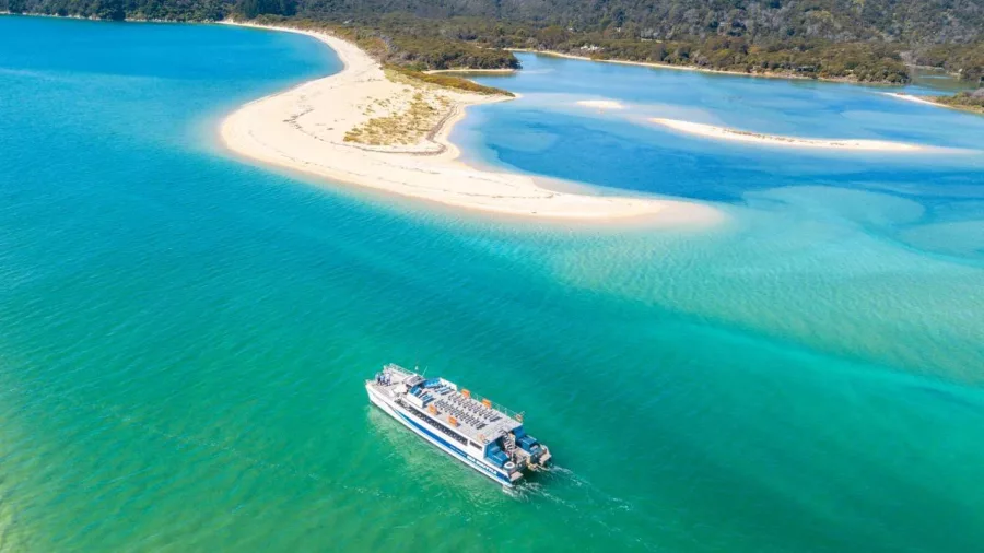 Abel Tasman Sea Shuttle cruising near Awaroa Inlet with golden sandbanks and turquoise water