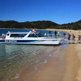 Hikers boarding the Abel Tasman Sea Shuttle from a sandy beach