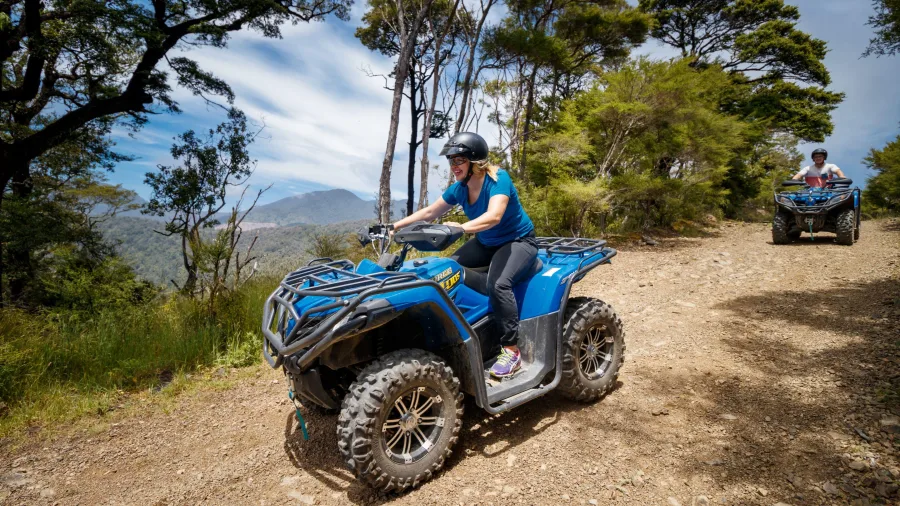 Woman riding a blue quad bike along a rugged forest trail on the Bayview Circuit at Cable Bay Adventure Park.