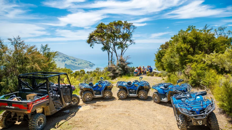 Quad bikes and a Polaris parked at a scenic lookout on the Bayview Circuit with views over Cable Bay in Nelson, New Zealand.
