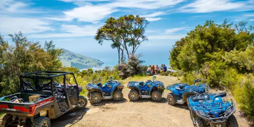 Quad bikes and a Polaris parked at a scenic lookout on the Bayview Circuit with views over Cable Bay in Nelson, New Zealand.