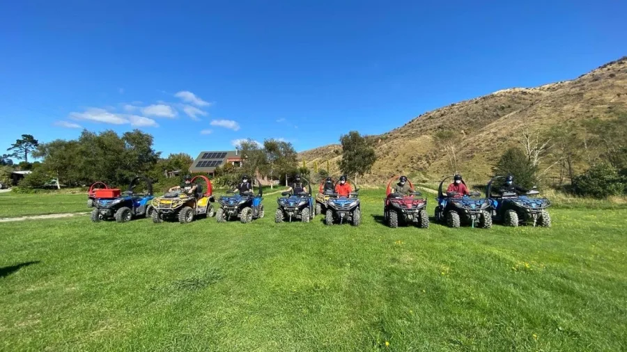 Group of riders lined up on quad bikes at Cable Bay Adventure Park with hills and blue sky in the background