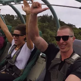 Group of friends smiling and raising their hands during a Skywire ride over native forest at Cable Bay Adventure Park in Nelson