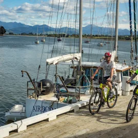 Cyclists passing a harbour with yachts on the Great Taste Trail in Nelson