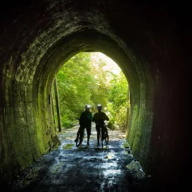Cyclists walking through Spooners Tunnel on the Great Taste Trail
