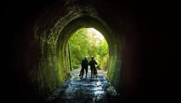 Cyclists walking through Spooners Tunnel on the Great Taste Trail