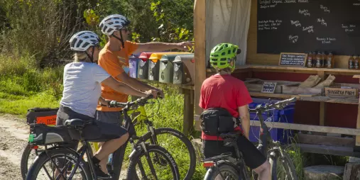 Cyclists visiting Little Shaggery Farm’s organic fruit and juice stall near Motueka