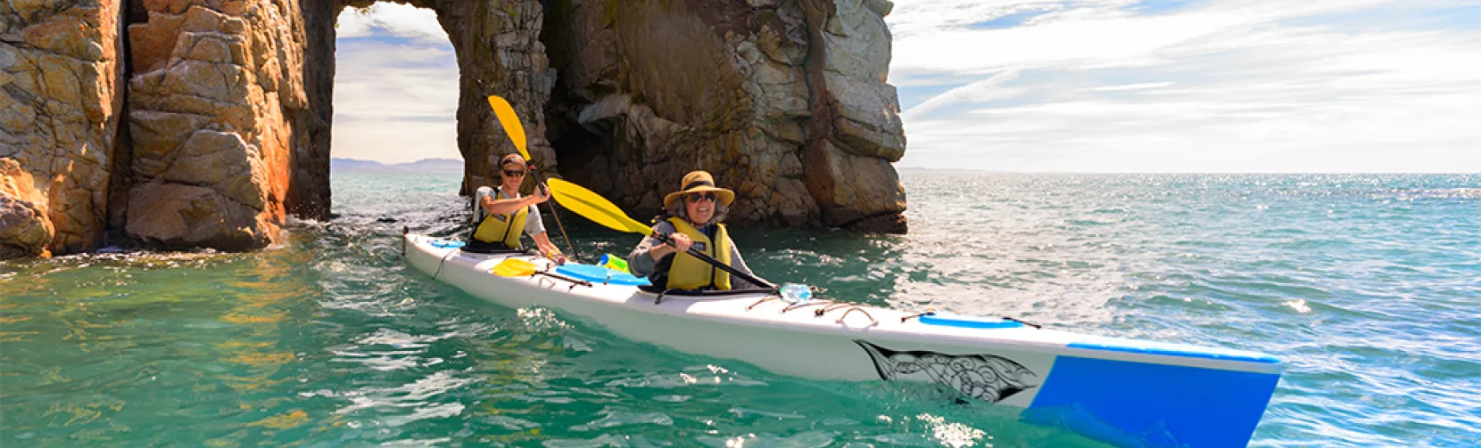 Two people kayaking through granite arch in Wainui Bay with Golden Bay Kayaks