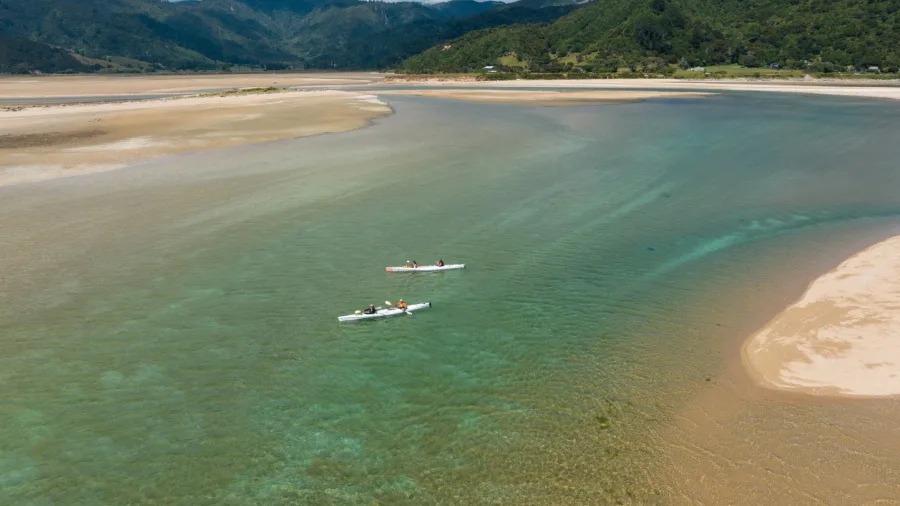 Aerial view of kayakers paddling through shallow estuary waters in Golden Bay, New Zealand