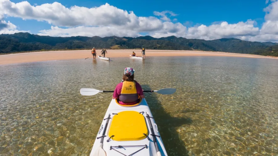 Kayaker approaching a sandbar in shallow clear waters at Golden Bay
