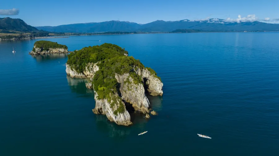 Kayakers paddling near rocky islets in clear waters off the coast of Golden Bay