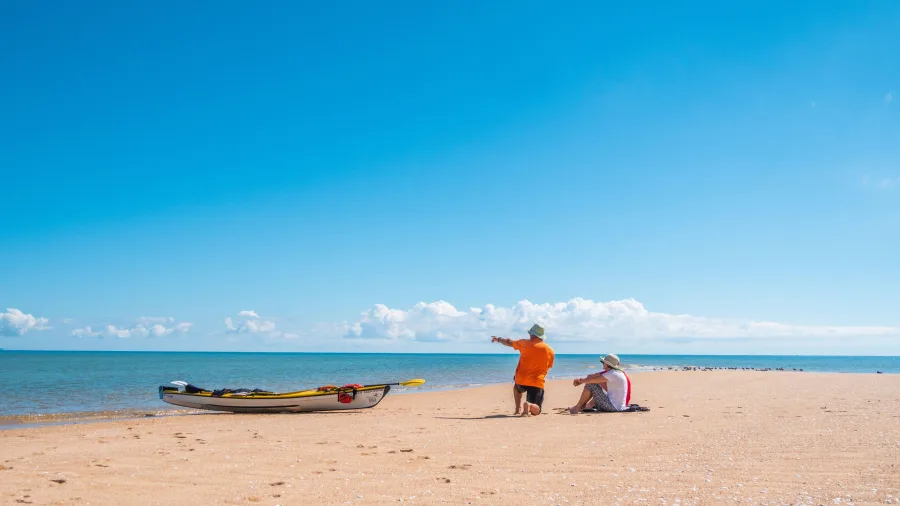Two kayakers resting on golden beach beside kayak in Golden Bay