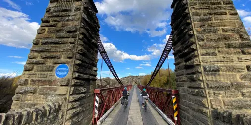 Cyclists riding toward Ophir Bridge on the Otago Central Rail Trail