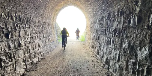 Cyclists riding through Prices Creek Tunnel on the Otago Central Rail Trail by eBike