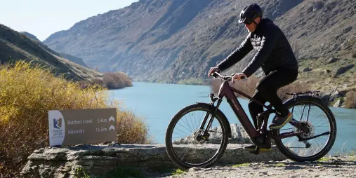Rider beside Roxburgh Gorge Trail sign pointing to Buddle Creek and Alexandra