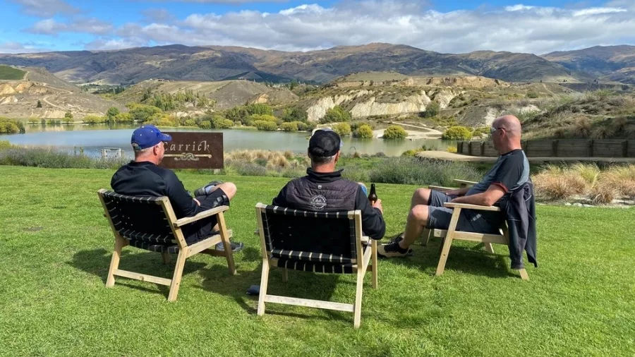 Three men relaxing at Carrick Winery in Bannockburn with lake and mountain views