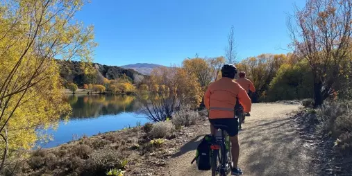 Cyclists riding along a riverside trail in Bannockburn during autumn