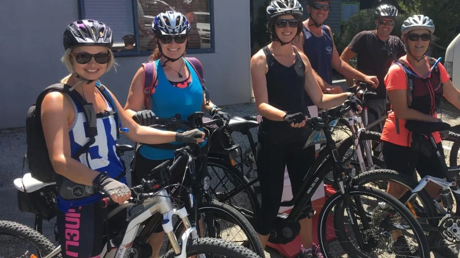 Group of smiling cyclists with e-bikes ready for a guided winery ride