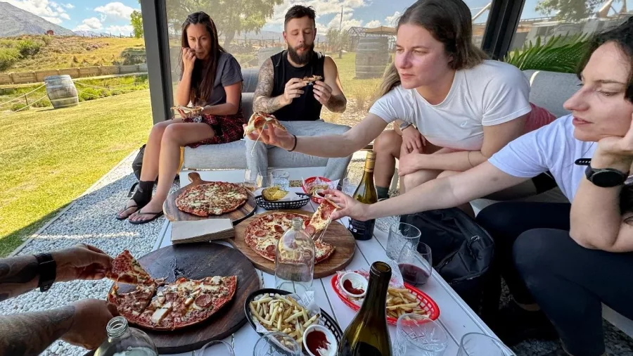 Group enjoying pizza and wine outdoors at a winery near the Lake Dunstan Trail in Central Otago