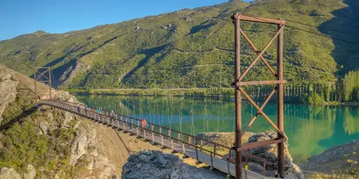 Cyclists cross the swing bridge on the Lake Dunstan Trail in Central Otago