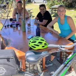 Group of women resting at an outdoor café with bikes parked nearby