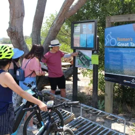 Group of cyclists gather around a map for a briefing on Tasman’s Great Taste Trail