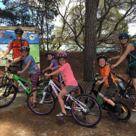 Family with kids on bikes at the Great Taste Trail entrance on Rabbit Island
