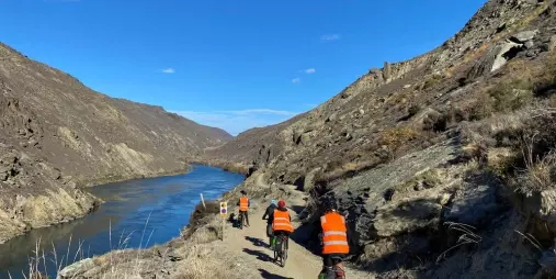 Cyclists riding along Roxburgh Gorge beside the Clutha River