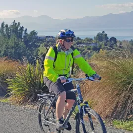 Cyclist riding on Pine Hill along the Great Taste Trail with views of Tasman Bay in the background