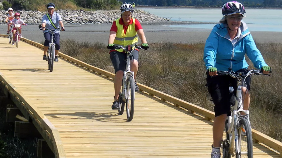 Group cycling on boardwalk during Magical Mapua tour