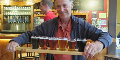 Man holding a tasting paddle at Eddyline Brewery in Mapua