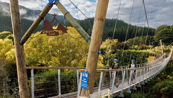 Cyclists crossing LubLows Leap suspension bridge on Baton River