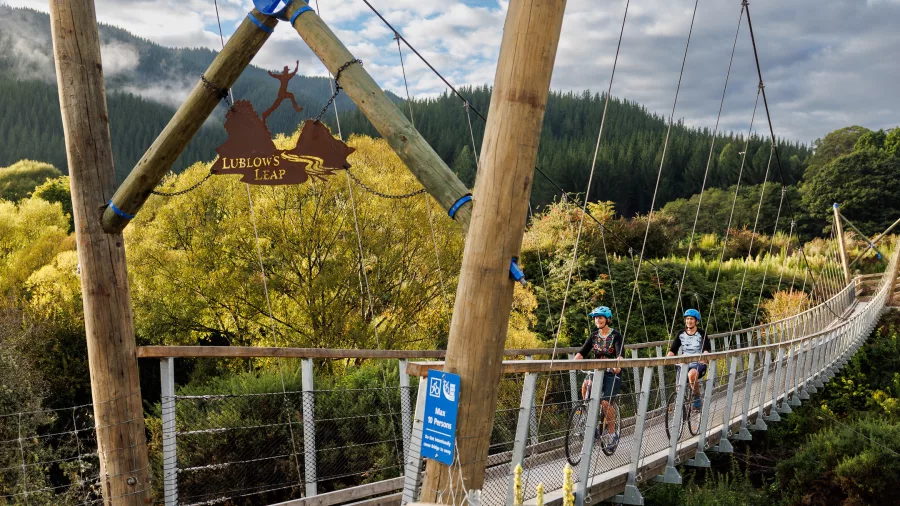 Cyclists crossing LubLows Leap suspension bridge on Baton River