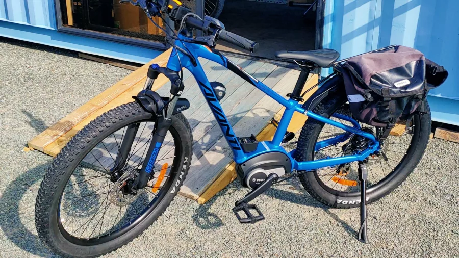 Extra extra small blue Avanti e-bike with pannier bag parked outside Nelson Cycle Hire