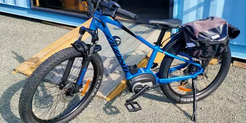Extra extra small blue Avanti e-bike with pannier bag parked outside Nelson Cycle Hire