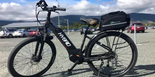 Step-through hybrid e-bike with wide tyres and rear carrier at Nelson Cycle Hire