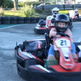 Young kids driving red go karts around a corner at the Fun Karts track at Pro Karts in Nelson