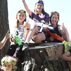 Group of adults and kids smiling with laser tag guns during an outdoor Pro Combat Laser Tag session in Nelson