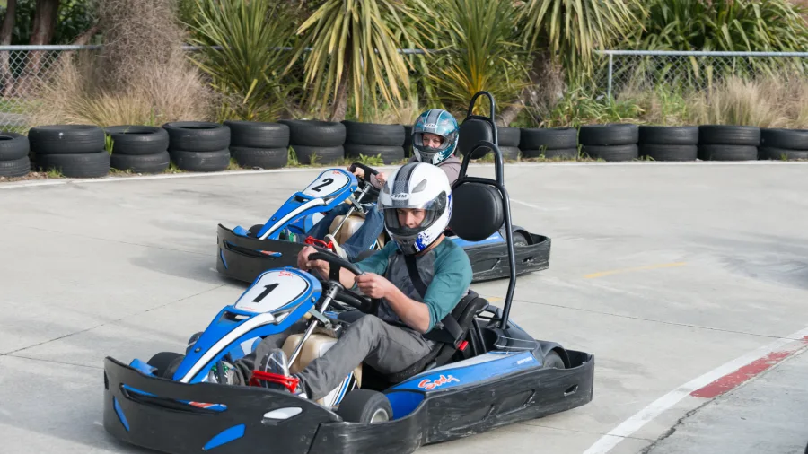Two drivers navigating a turn on the outdoor go kart track at Pro Karts in Nelson