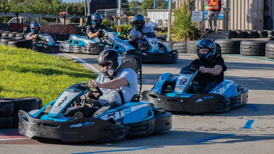 Group of go kart drivers taking a turn on the outdoor track at Pro Karts in Nelson with a marshal observing