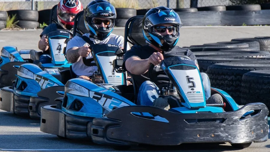 Three adult drivers racing go karts closely together on the track at Pro Karts in Nelson