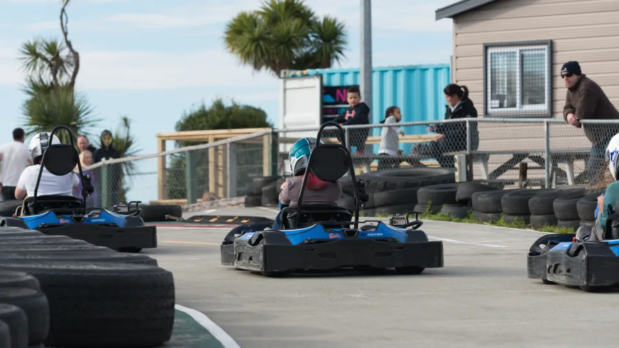 Go karts racing around the outdoor track at Pro Karts in Nelson with spectators in the background
