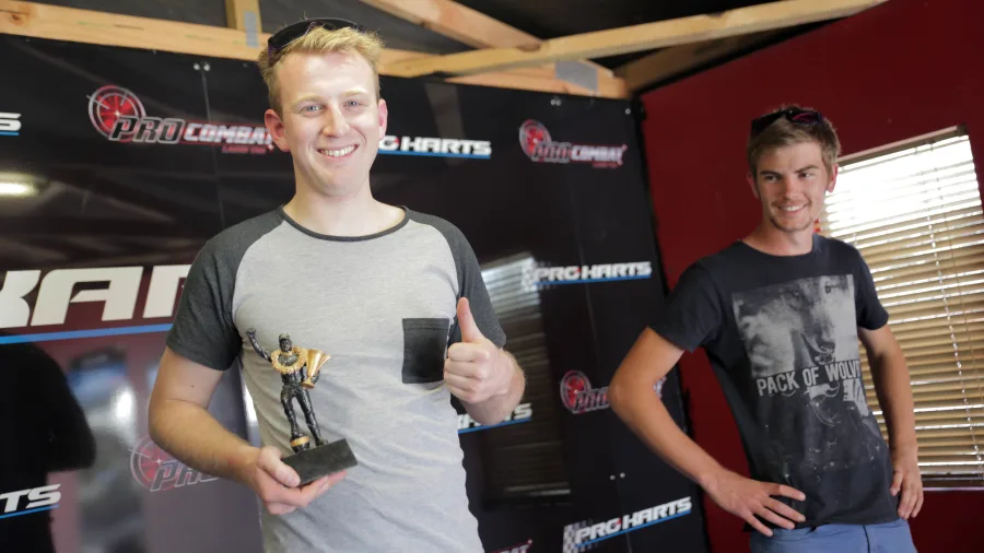 Smiling man holding a trophy at the Pro Karts winner podium area in Nelson