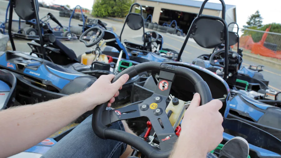 First-person view of hands gripping a go kart steering wheel at Pro Karts in Nelson