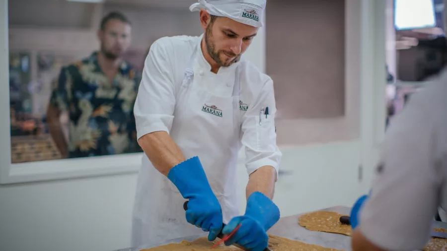 Chocolatier cutting caramel slab at Makana Boutique Chocolate Factory in Kerikeri