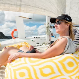 Woman relaxing on a yellow bean bag during a catamaran cruise in the Bay of Islands