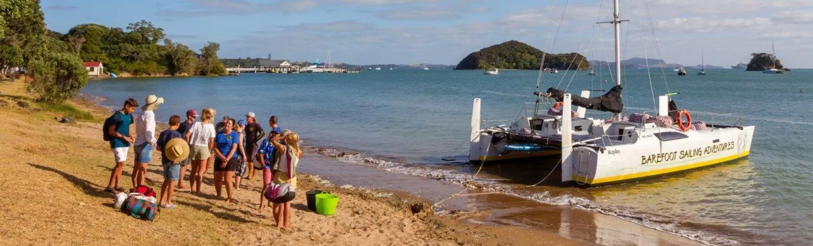 Group of people preparing to board a catamaran from the beach in the Bay of Islands