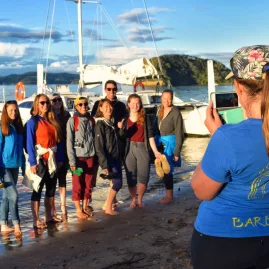 Group of barefoot travellers posing for a photo after a sailing trip in the Bay of Islands